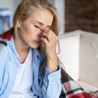 Fatigue and upset woman touching nose bridge feeling eye strain or headache, trying to relieve pain. Sick and exhausted female spending day at home. Depressed lady feeling weary dizzy